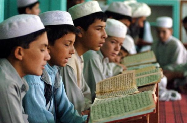 Afghan boys read the Quran at the Abdullah ebni-Abas madrassa – school – in Ghazni province, 05 August 2007. The formation of madrassas can probably be traced to the early Islamic custom of meeting in mosques to discuss religious issues when people seeking religious knowledge tended to gather around certain more knowledgable Muslims.  AFP PHOTO/SHAH Marai (Photo credit should read SHAH MARAI/AFP/Getty Images)